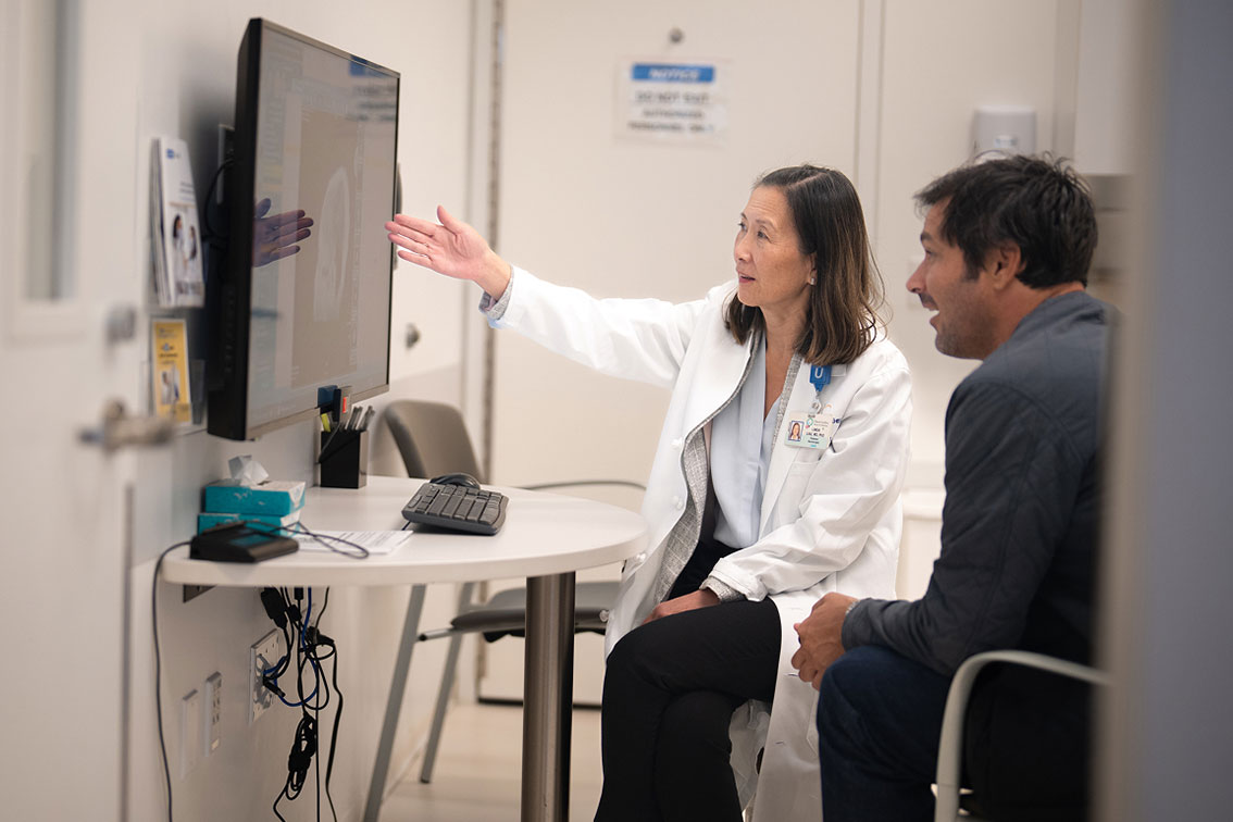 Researcher Linda Liau with a patient looking at a scan